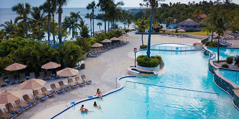Resort pool with loungers and palm trees.